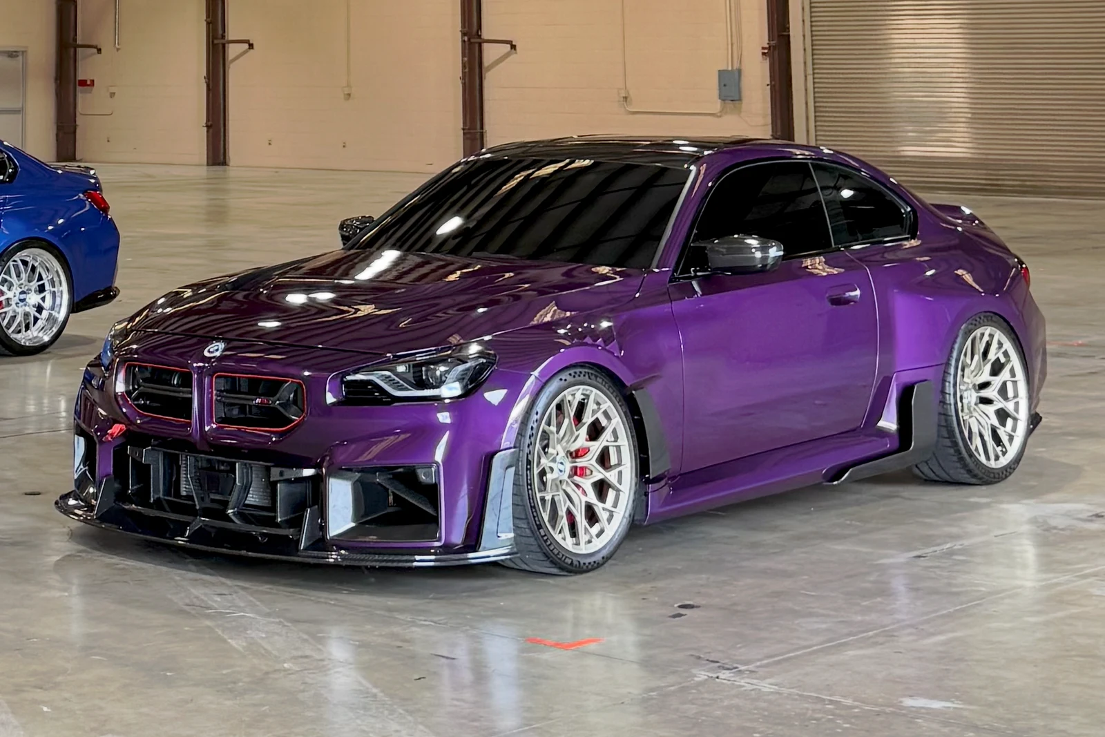 Purple BMW G87 M2 with carbon front lip and side skirts inside a warehouse