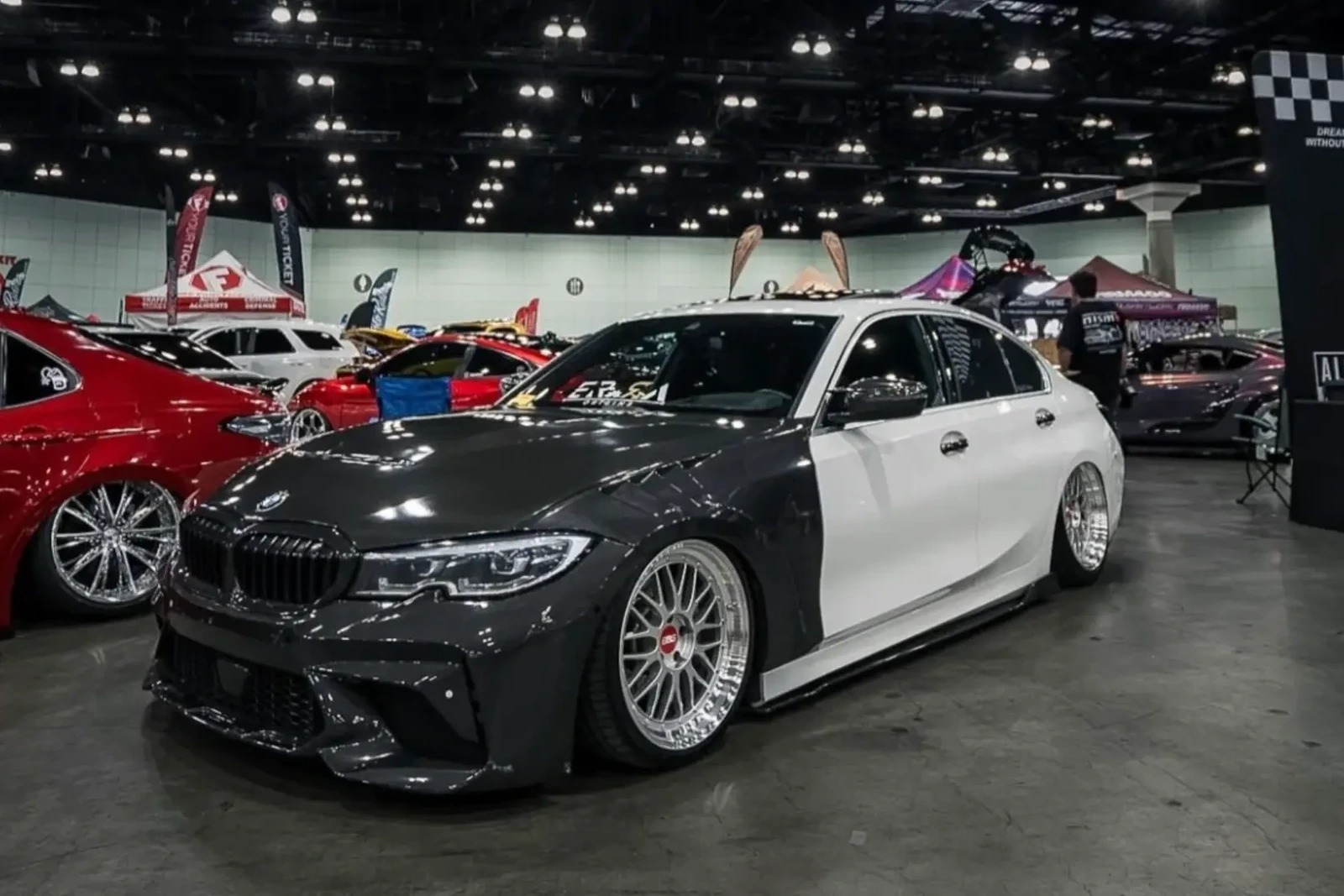 BMW G20 3 Series with split black-and-white wrap at an indoor car show